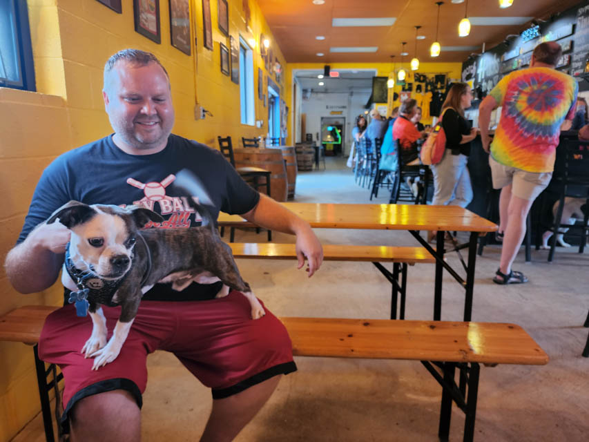 A patron inside brewery with dog on his lap